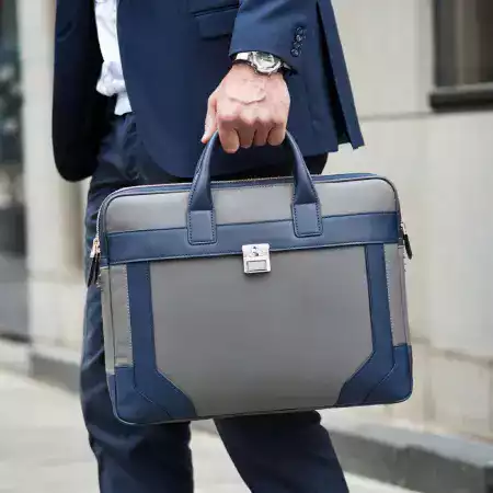 Stylishly dressed man standing beside a vintage motorcycle, with a ManBagCo messenger bag slung over his shoulder