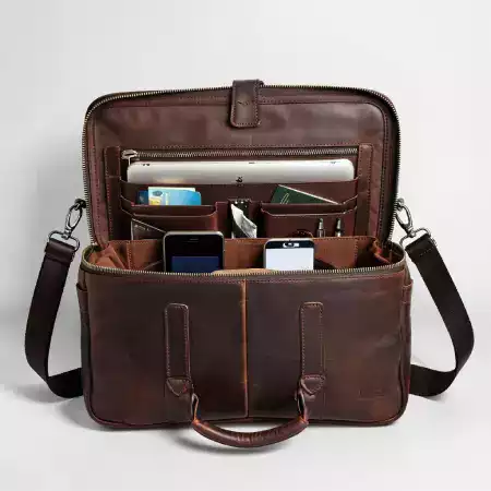 Close-up of a man's hand adjusting the strap of a ManBagCo messenger bag, showcasing everyday functionality and style
